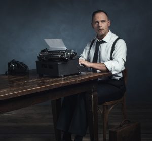 Retro 1940 office worker behind desk with typewriter and telephone.